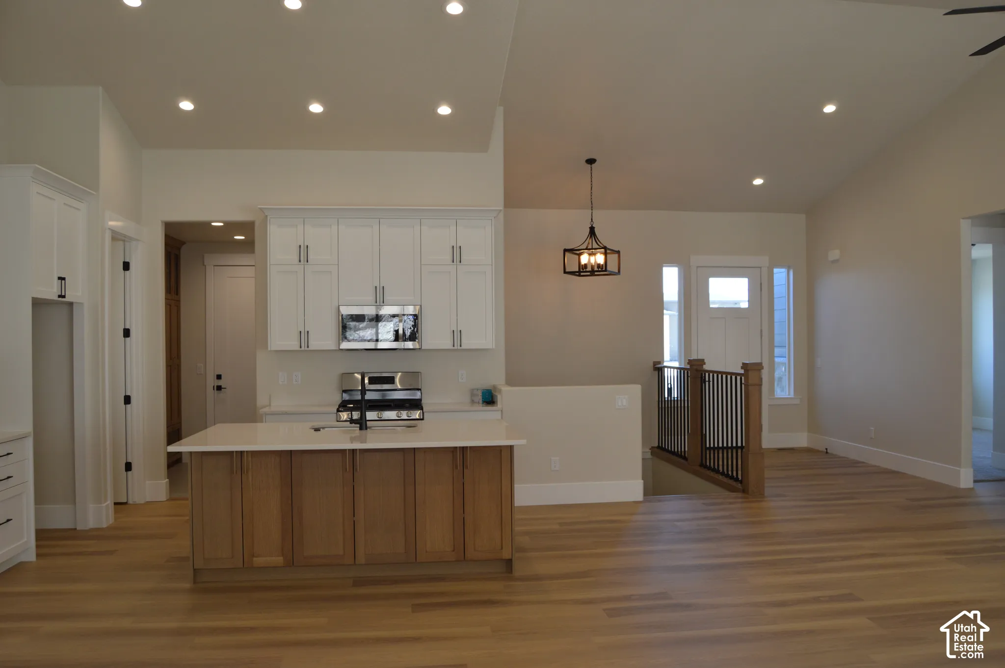 Kitchen featuring white upper cabinetry, a wood-finish base island, vaulted ceilings, recessed lighting, and wood-finish flooring