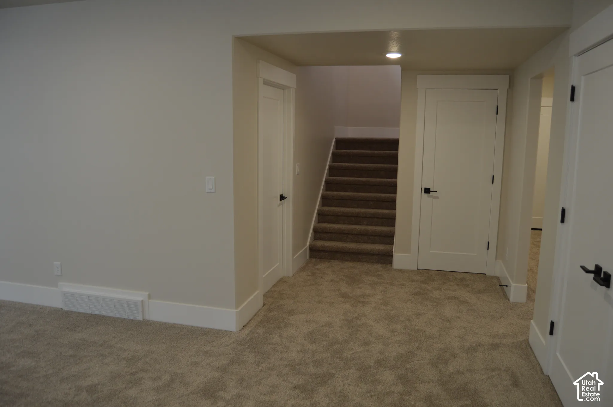 Interior area featuring neutral-toned carpeting, two-panel shaker-style interior doors, matte black hardware, and recessed ceiling lighting