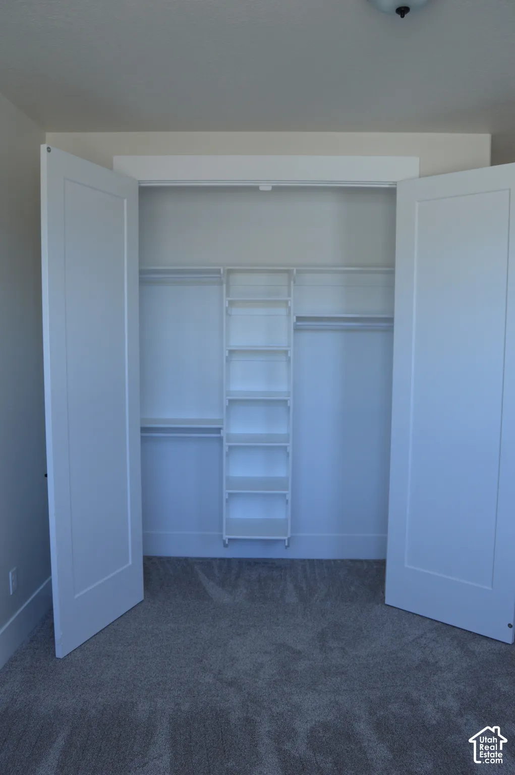 Reach-in closet featuring shaker-style double doors and custom white built-in shelving with integrated rods
