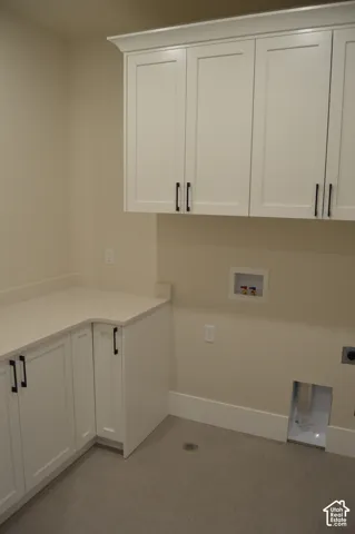 Laundry room featuring white Shaker-style cabinetry, quartz countertop, and neutral flooring