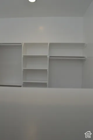 Custom white built-in shelving featuring integrated hanging rods and multiple storage compartments