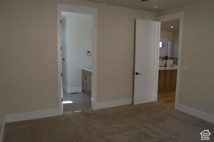Neutral-toned interior space featuring carpeting, shaker-style interior doors with matte black hardware, and crisp white casing around door frames