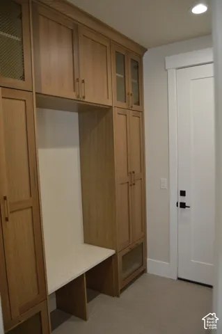 Built-in floor-to-ceiling cabinetry with wood-finish doors, glass-panel upper accents, metal mesh detailing, quartz-surface bench seating, and matte black hardware