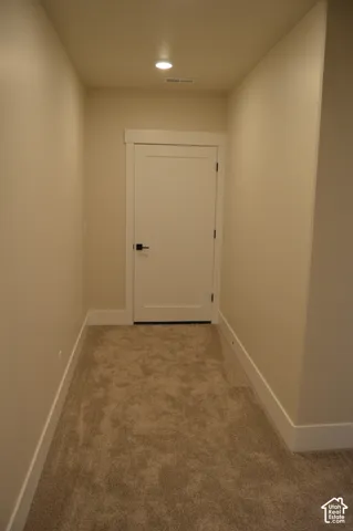 Neutral-toned wall-to-wall carpeting, solid-core interior door with flat-panel design, and matte black lever hardware
