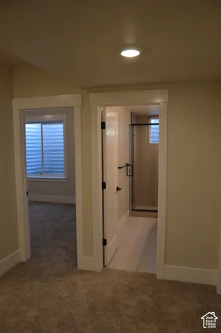 Solid-core doors with matte black hardware, recessed ceiling lighting, wall-to-wall carpeting, and a tiled shower enclosure