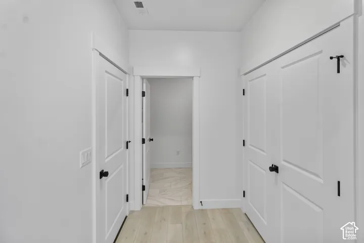 Interior area featuring wood-finish flooring, two-panel interior doors, matte black hardware, and stone-finish flooring within the threshold