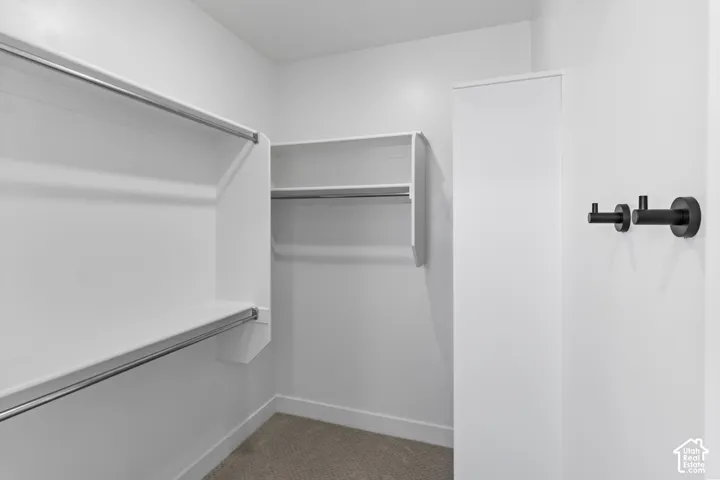 Storage space featuring white wall-mounted shelving with integrated metal clothing rods, a full-height white storage cabinet, and matte black hardware hooks