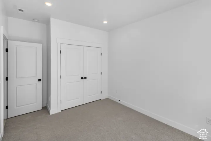Neutral interior featuring wall-to-wall carpeting, dual-panel interior doors, crisp white millwork, and recessed ceiling lighting