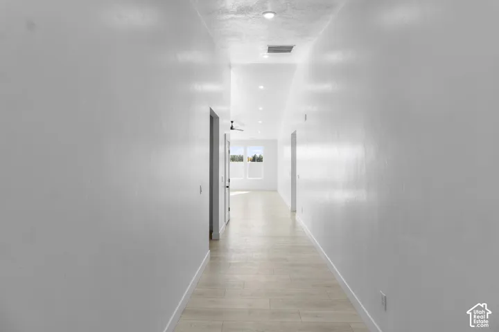 Hallway featuring high ceilings, wood-finish flooring, and recessed lighting