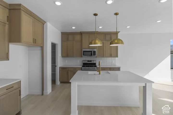 Kitchen featuring wood-finish cabinetry, quartz countertops, central island, brass-tone pendant lighting, and recessed ceiling lights