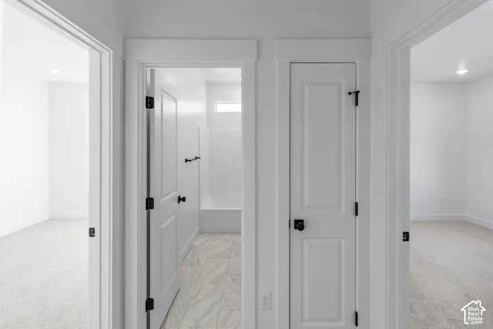 Interior hallway featuring high-contrast matte black hardware, crisp white doors with square-profile casings, and patterned tile flooring