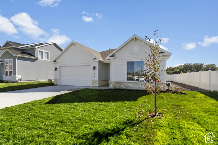 Single-story exterior featuring white horizontal siding, stone veneer accents, an attached two-car garage, and a concrete driveway