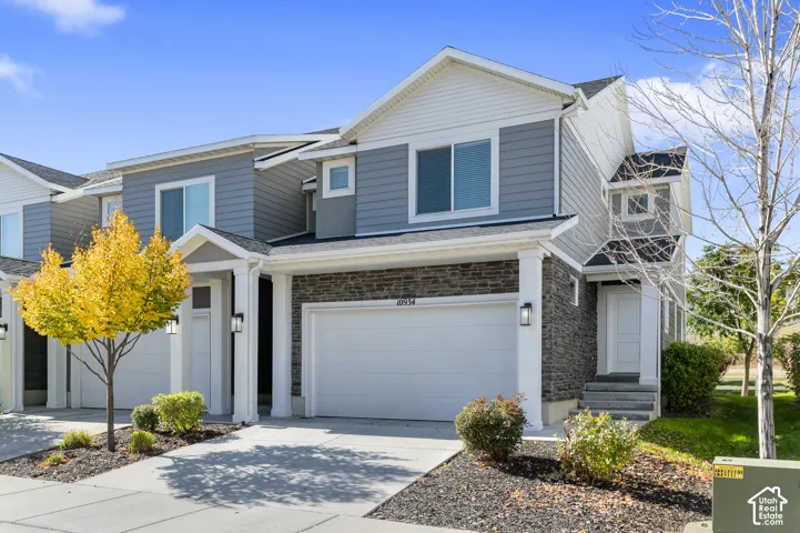 Two-story exterior featuring stone veneer siding, horizontal lap siding, a gabled roofline, a two-car garage, and a covered entryway with column supports