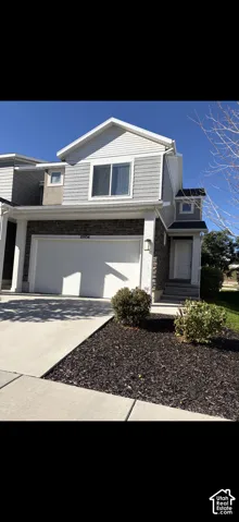 Two-story exterior featuring a mix of horizontal lap siding and shake-style accents, stone veneer lower facade, attached two-car garage, and concrete driveway