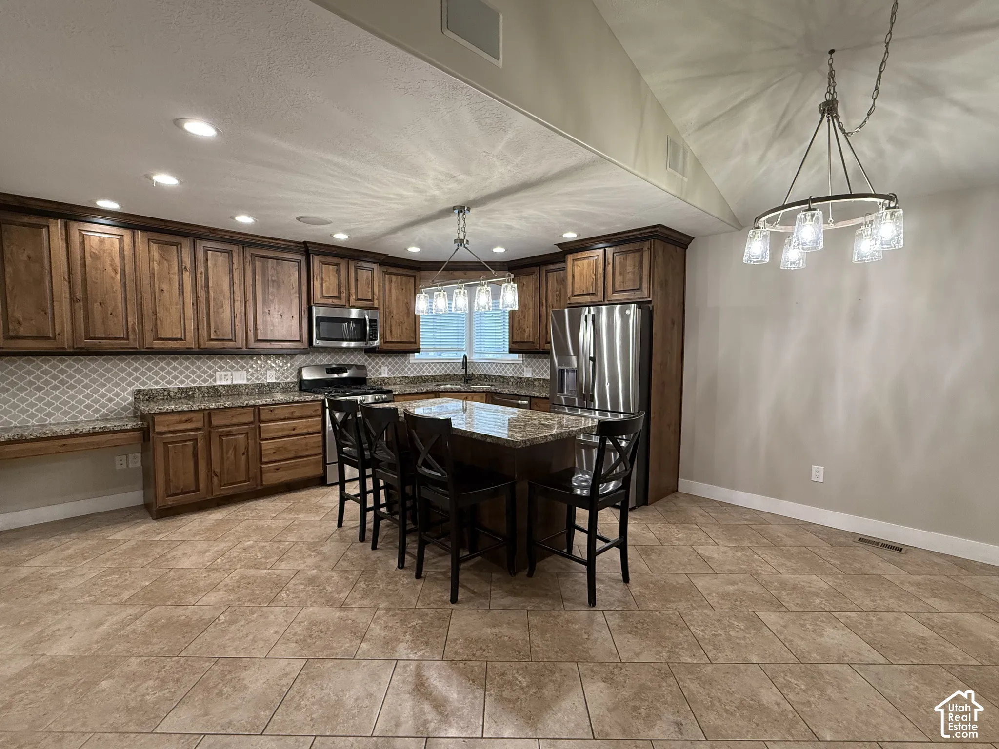 Kitchen featuring custom wood cabinetry, stone countertops, tiled backsplash, large center island, and recessed lighting