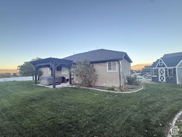 Backyard featuring a manicured lawn, a covered wooden pergola, a concrete patio, and a detached storage shed