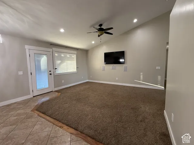 Vaulted ceilings featuring recessed lighting, a ceiling fan, tiled flooring, integrated wall speakers, and a glass-paneled exterior door