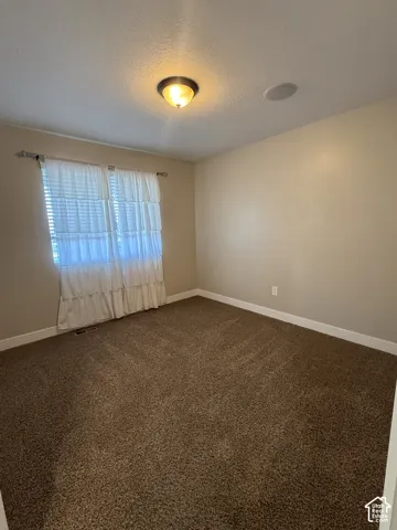 Neutral interior space featuring wall-to-wall carpeting, a flush-mount ceiling light fixture, and an integrated ceiling speaker