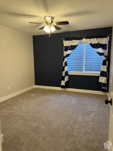 Room featuring wall-to-wall carpeting, a dark-toned accent wall, and a multi-light ceiling fan