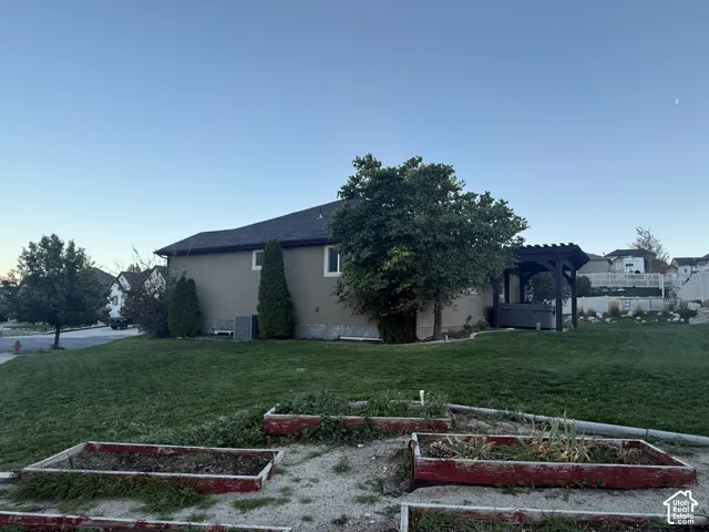 Exterior featuring a manicured lawn, built-in wooden garden boxes, and a covered pergola