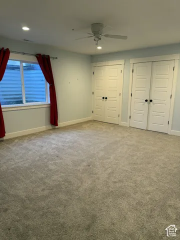 Neutral-toned carpeting, recessed ceiling lighting, a white ceiling fan, and double closets featuring five-panel doors with matte black hardware