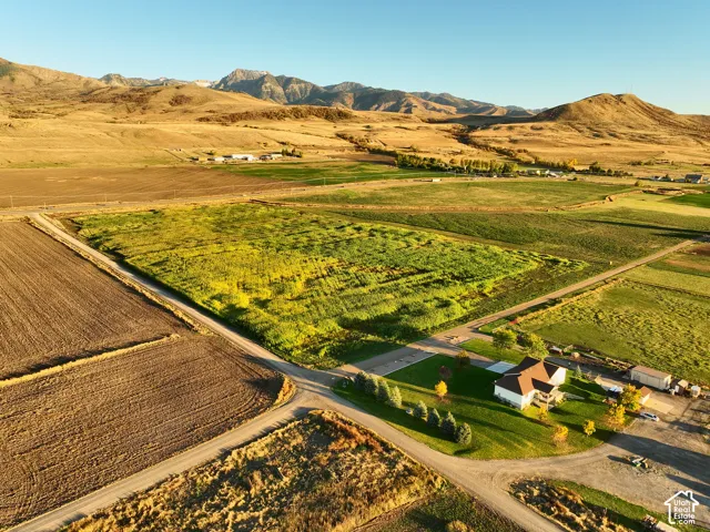 Aerial perspective of expansive acreage looking South East featuring open fields, paved road access, and a mountain range backdrop