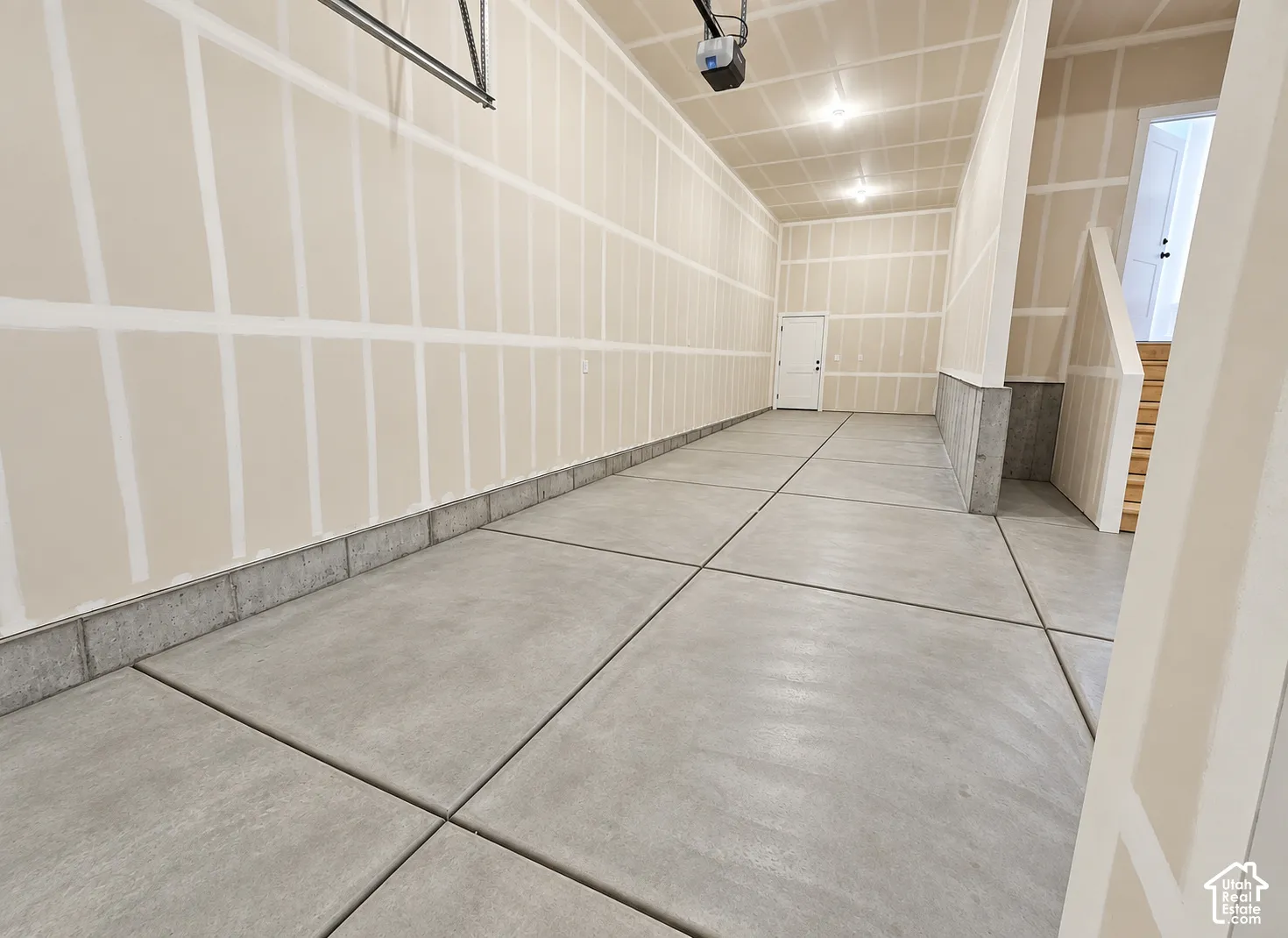 Spacious multi-bay garage featuring concrete flooring, finished drywall, overhead lighting, and an access door