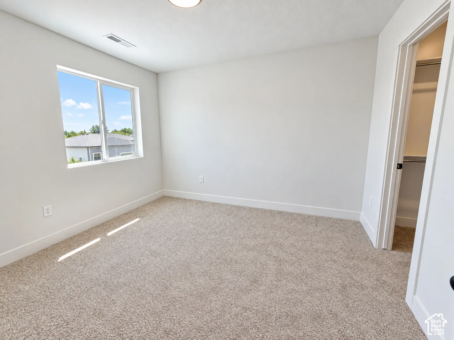 Neutral-toned carpeted flooring, white interior walls, and an accessible closet with built-in shelving
