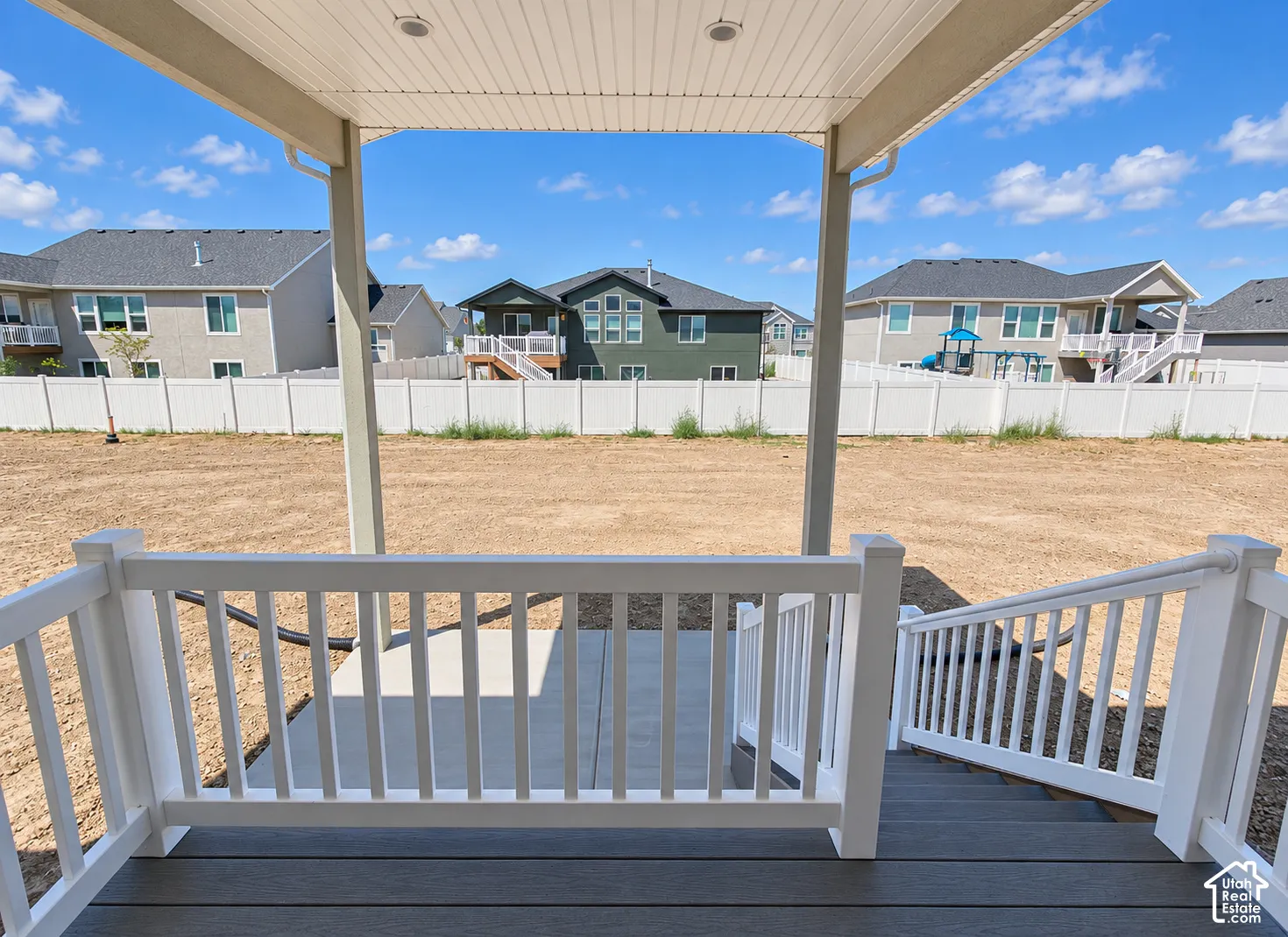 Covered patio featuring composite decking, white vinyl railings, recessed lighting, and a concrete landing