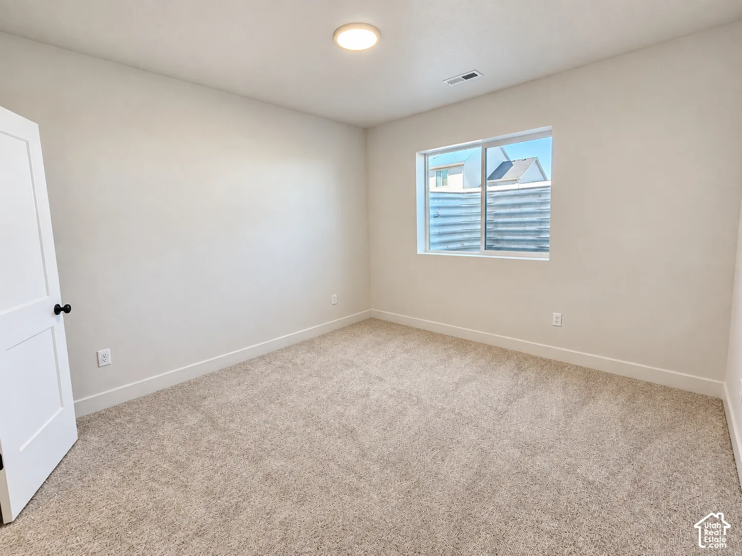 Neutral-toned interior featuring wall-to-wall carpeting, a sliding window, and a multi-panel door with matte black hardware