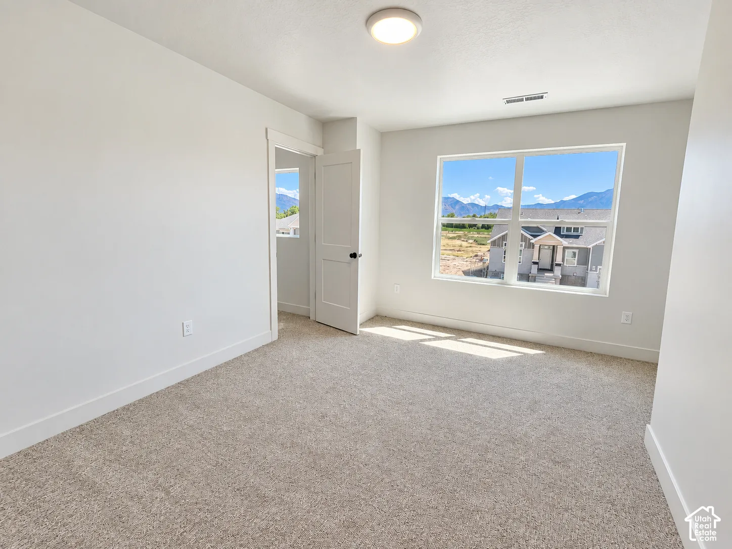 Neutral wall tones, wall-to-wall carpeting, large window with mountain scenery, and two-panel interior door