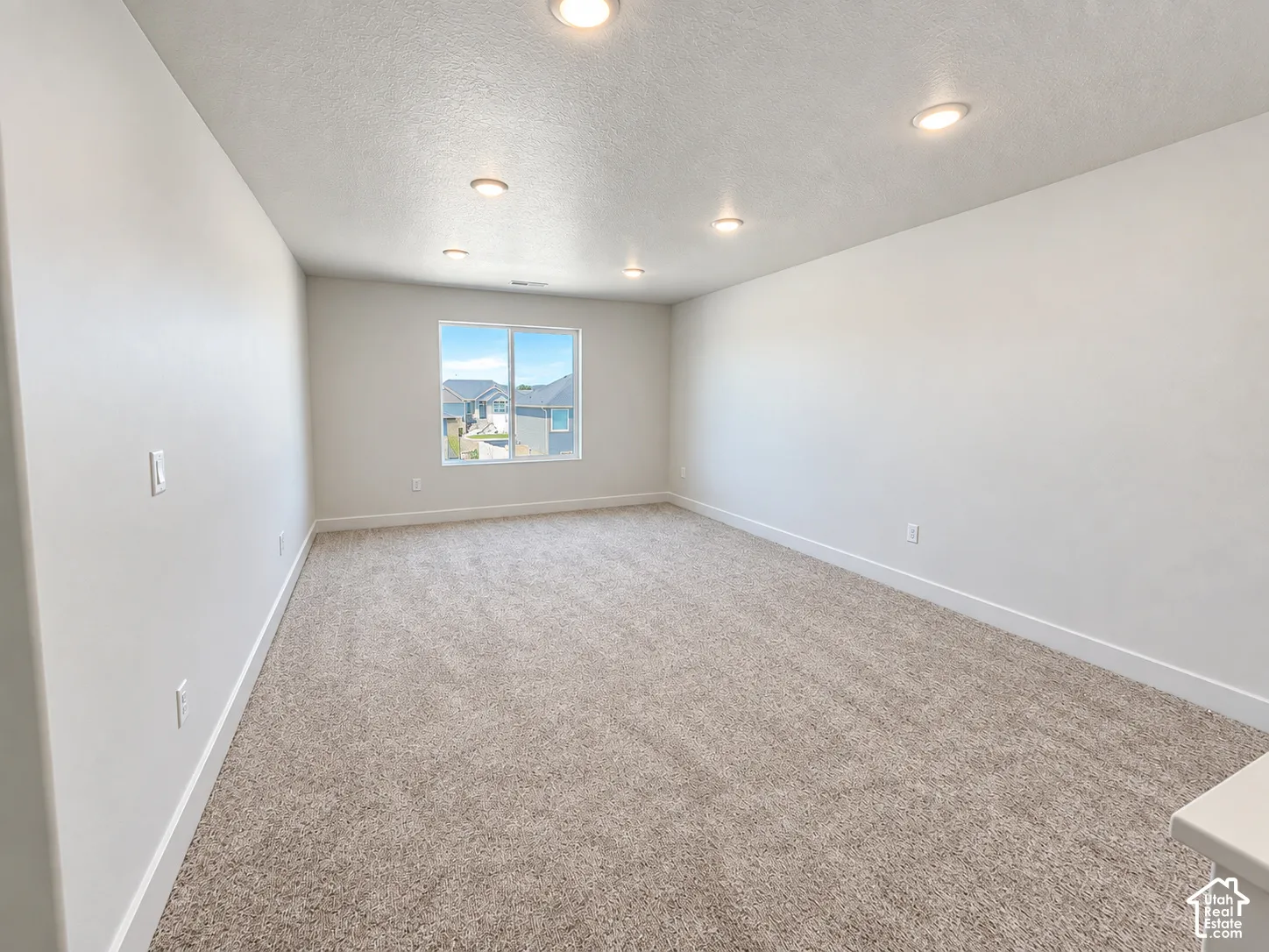 Neutral-toned carpeted flooring, recessed lighting, and a single-pane window