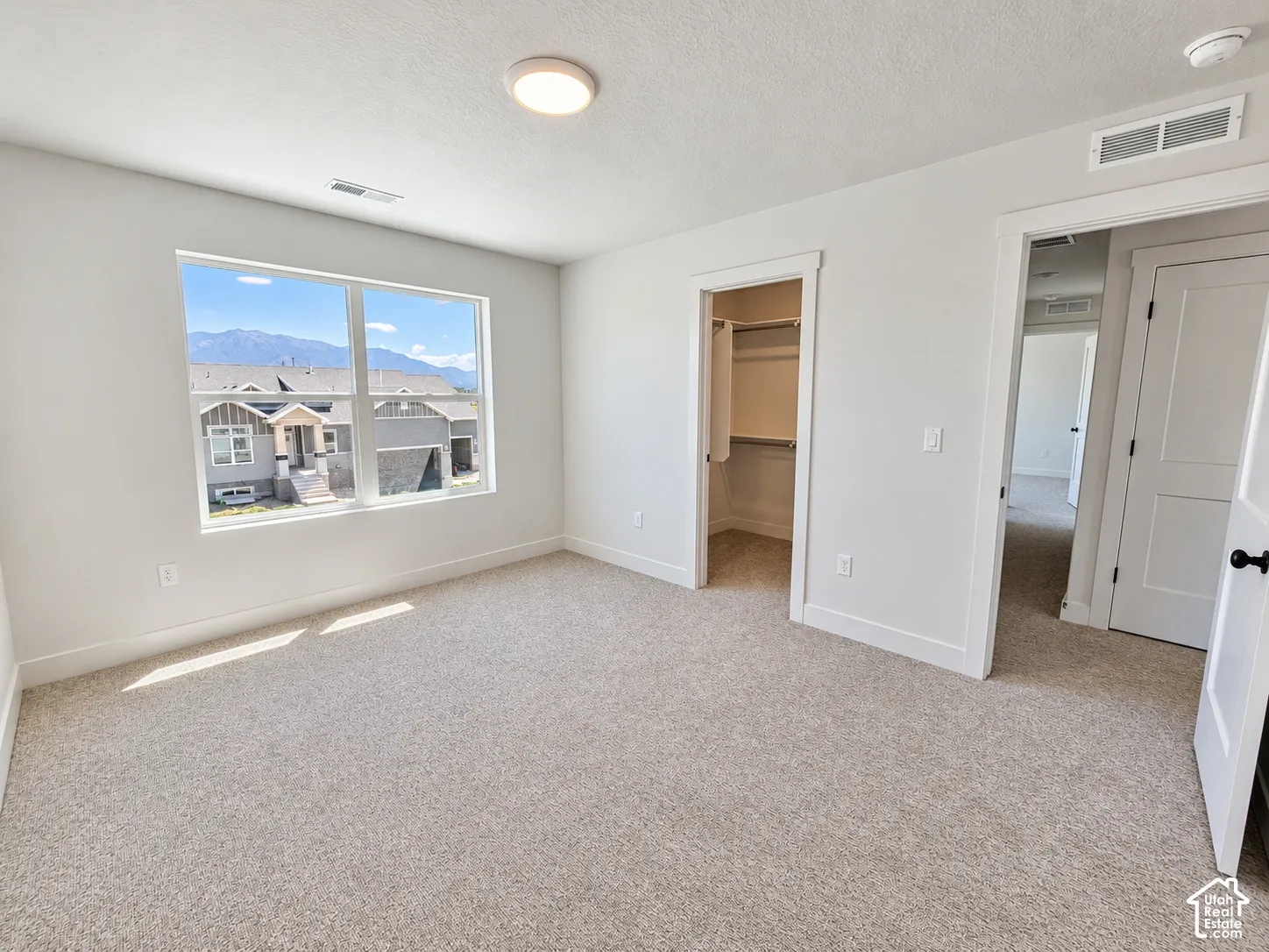 Interior room featuring neutral carpeting, a walk-in closet with built-in shelving, multi-pane window with mountain scenery, and two-panel interior doors