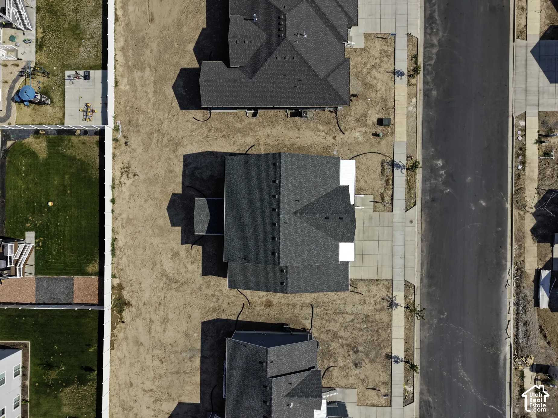 Aerial perspective of property featuring a multi-gabled shingle roof, concrete driveway, and concrete sidewalk