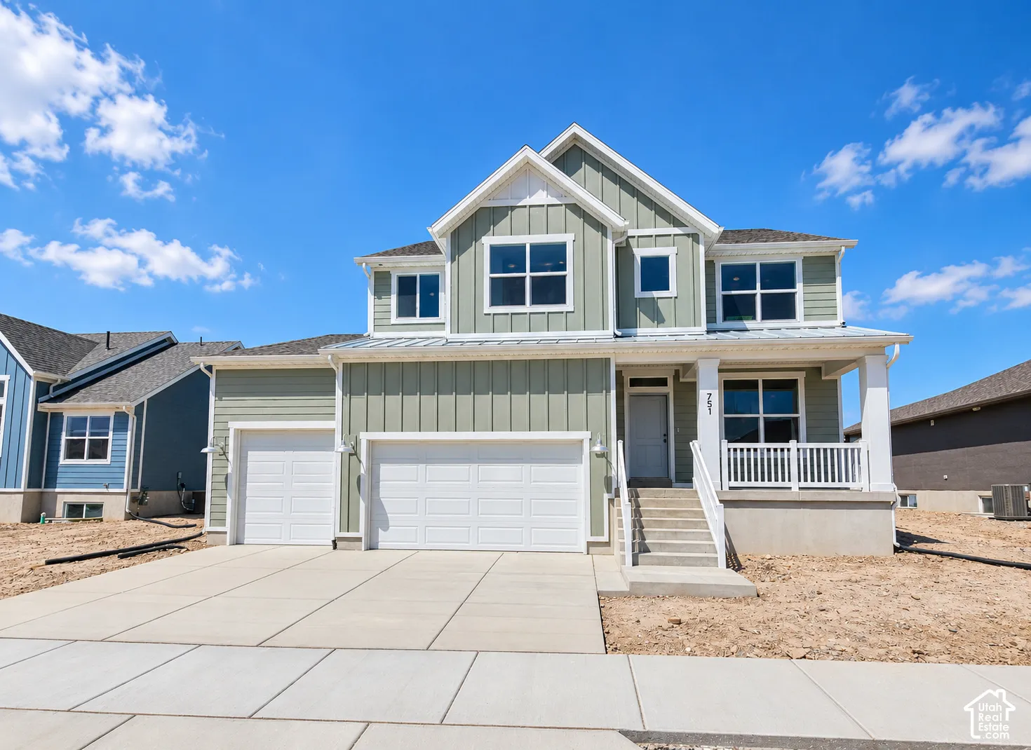 Two-story exterior featuring board-and-batten siding, a covered front porch with white railings, a three-car garage, and concrete driveway