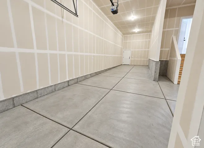 Spacious multi-bay garage featuring concrete flooring, finished drywall, overhead lighting, and an access door