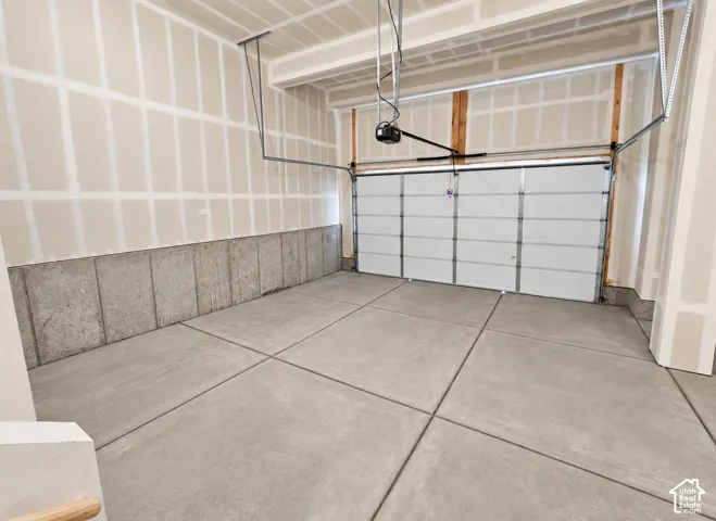 Finished garage featuring exposed concrete foundation walls, smooth concrete flooring, and an automated overhead door system