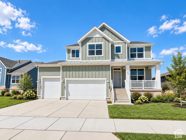 Two-story residence featuring vertical siding, a covered front porch with white railing, a three-car garage, and concrete driveway