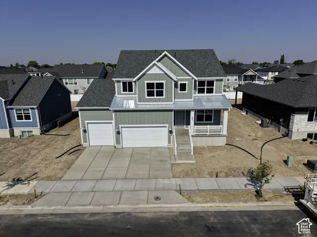Two-story residence featuring vertical siding, a metal accent roof over the entry, asphalt shingle roofing, and an attached three-car garage