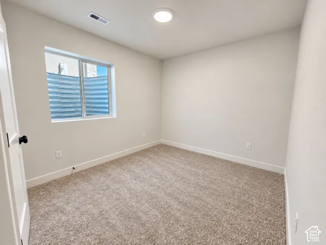 Neutral-toned wall-to-wall carpeting, crisp white walls, and a recessed window with an integrated corrugated steel egress well