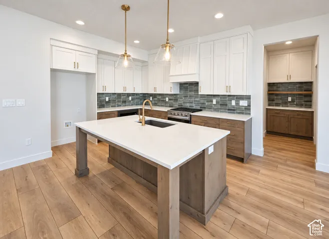 Kitchen featuring two-tone cabinetry, wood-finish flooring, a large island with a composite countertop, recessed lighting, and glass pendant fixtures