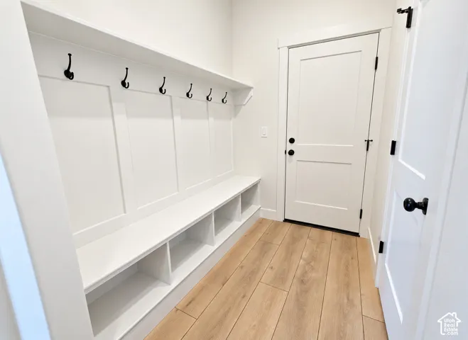 Built-in mudroom bench with board-and-batten detailing, overhead shelf, integrated cubbies, matte black hardware, and wood-finish flooring