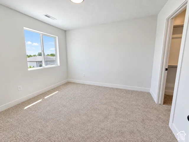 Neutral-toned carpeted flooring, white interior walls, and an accessible closet with built-in shelving