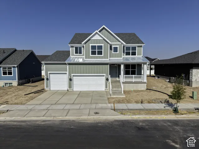 Two-story exterior featuring vertical siding, a metal-accented front porch, a three-car garage, and a concrete driveway