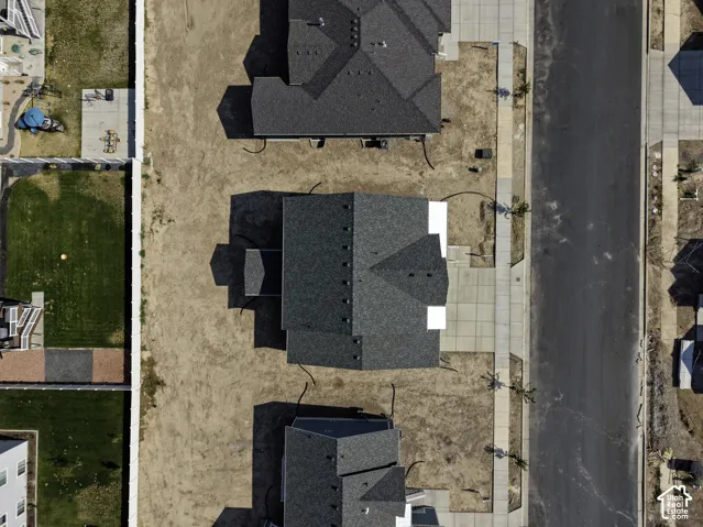 Aerial perspective of property featuring a multi-gabled shingle roof, concrete driveway, and concrete sidewalk