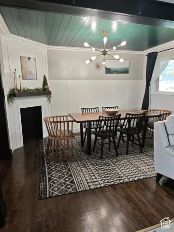 Dining area featuring wood-finish flooring, white wainscoting, a fireplace with a wood mantel, a green tongue-and-groove ceiling, and a multi-arm metallic chandelier