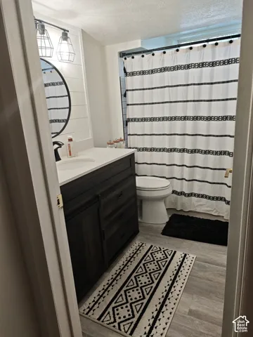 Bathroom featuring a dark wood-finish vanity, light-toned countertop, shiplap wall accents, round-frame mirror, and industrial-style dual pendant lighting