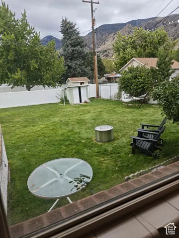 Fenced backyard featuring a manicured lawn, detached storage shed, and mountain backdrop