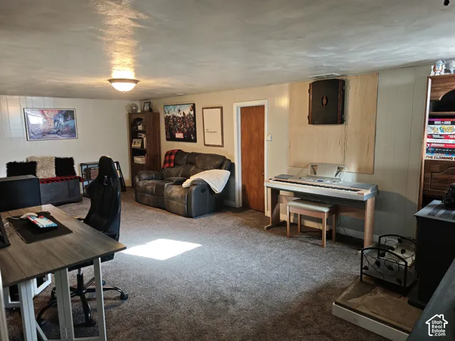 Interior space featuring wall-to-wall carpeting, wood-paneled walls, flush-mount ceiling lighting, and a hearth area with a stone base