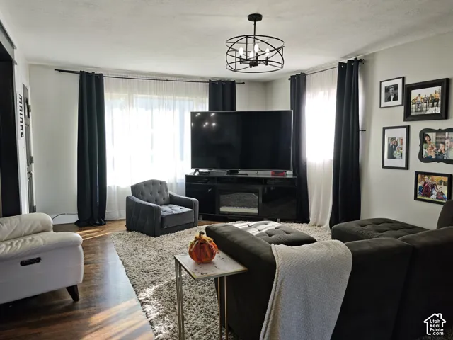 Living area featuring dark-tone wood-finish flooring, a multi-light spherical metal chandelier, and large windows